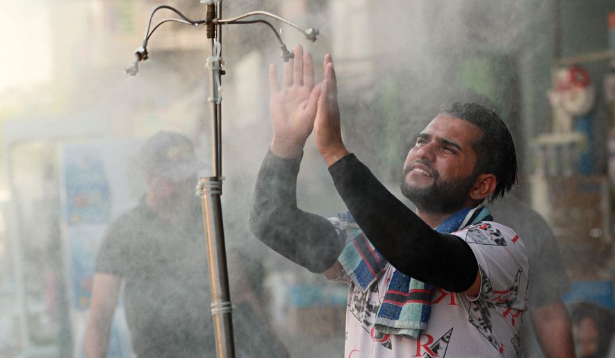 A man cools off from the summer heat under an open air shower in Baghdad, Iraq, Sunday, July 5, 2020. (AP Photo/Hadi Mizban)