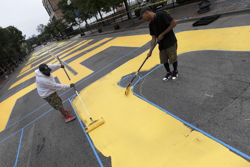 Lee Beard, left, and Mar, no last name given, paint the phrase Black Lives Matter on Washington Street, Sunday, July 5, 2020, in the Roxbury neighborhood of Boston. (AP Photo/Michael Dwyer)