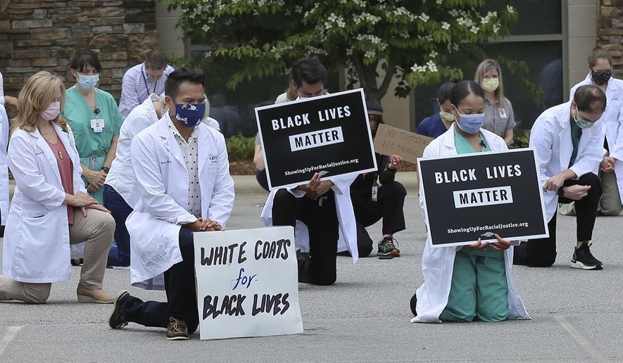 In this June 5, 2020 photo provided by the Mountain Area Health Education Center, physicians, residents and staff from the facility in Asheville, N.C., take a knee to show support for renewed calls for racial justice after the police killing of George Floyd. Government statistics from late January through May 30 suggest an increase in U.S. deaths from chronic diseases compared with historical trends. They include 7,000 excess deaths from hypertension, about 4,000 from diabetes and 3,000 from strokes -- all conditions that disproportionately affect Blacks, although the data don’t include race. (Brenda Benik/MAHEC via AP)
