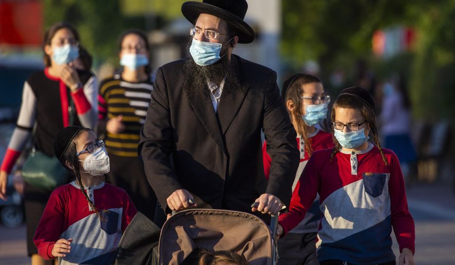 Ultra-Orthodox Jews wait to cross a closed road to go to their homes as they wear protective face masks to help curb the spread of the coronavirus in Ashdod, Israel, Thursday, July 2, 2020. Coronavirus restrictions have gone into effect in Israel after the number of new cases there hit a record high the previous day, while the West Bank prepares to go into lockdown. (AP Photo/Ariel Schalit)