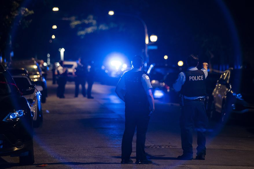 Chicago police officers investigate the scene of a shooting in Chicago on Sunday, July 5, 2020. At least a dozen people, including a 7-year-old girl at a family party and a teenage boy, were killed in Chicago over the Fourth of July weekend, police said. Scores of people were shot and wounded. (Ashlee Rezin Garcia/Chicago Sun-Times via AP)