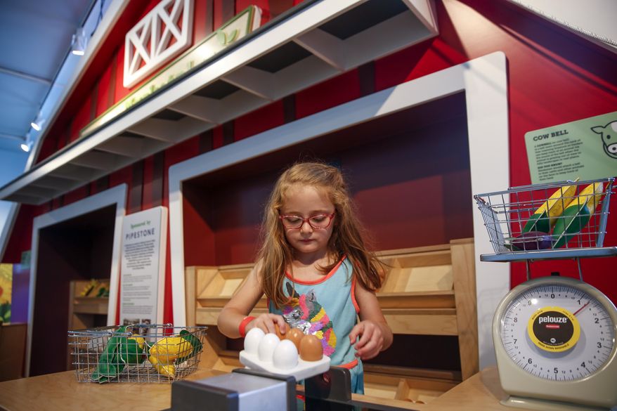 Veronica Adamson, 4, plays in the marketplace exhibit during the opening of Washington Pavilion's "Grow It!," on Thursday, June 25, 2020 in Sioux Falls, S.D. A bright, red barn and puffy, white clouds welcomes people into the Washington Pavilion’s newest exhibition, “Grow It!” The addition to the Kirby Science Discovery Center was revealed June 25 and features 3,000 square feet of interactive agriculture experiences.(Abigail Dollins/The Argus Leader via AP)