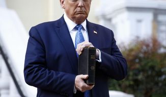 FILE - In this June 1, 2020, file photo, President Donald Trump holds a Bible as he visits outside St. John&#39;s Church across Lafayette Park from the White House in Washington. Part of the church was set on fire during protests on Sunday night. (AP Photo/Patrick Semansky, File)