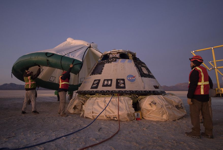 FILE - In this Sunday, Dec. 22, 2019 photo made available by NASA, Boeing, NASA, and U.S. Army personnel work around the Boeing Starliner spacecraft shortly after it landed in White Sands, N.M. On Tuesday, July 7, 2020, NASA officials said they have identified 80 corrective actions for safety, mostly involving software, that must be implemented before the Starliner capsule launches again. The previous count was 61.  (Bill Ingalls/NASA via AP)