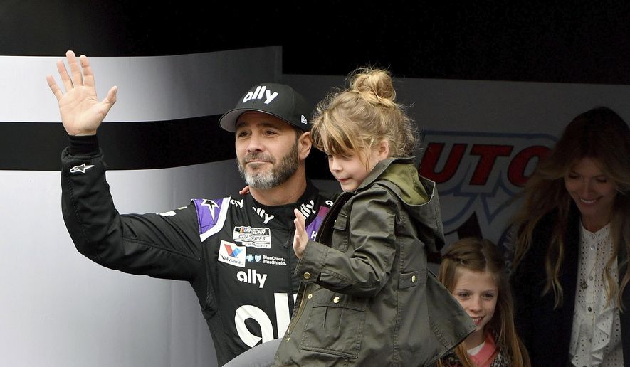 FILE - In this March 1, 2020, file photo, Jimmie Johnson is introduced to the crowd during activities as he carries his youngest daughter Lydia as his oldest daughter Genevieve and wife Chandra follow prior to a NASCAR Cup Series auto race in Fontana, Calif. This year has hardly been the farewell tour Jimmie Johnson envisioned when he said 2020 would be his final season of full-time NASCAR racing. The seven-time champion has had to say his goodbyes at empty race tracks absent of all fanfare and now his streak of 663 consecutive races has ended because Johnson tested positive for the coronavirus. (AP Photo/Will Lester, File)