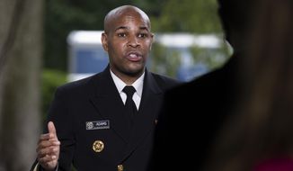 U.S. Surgeon General Jerome Adams does a television interview on the North Lawn of the White House, Tuesday, July 7, 2020, in Washington. (AP Photo/Alex Brandon)