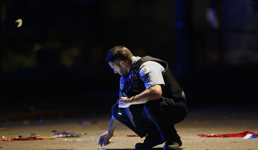 In this July 5, 2020, file photo, an officer investigates the scene of a shooting in Chicago. Still reeling from the coronavirus pandemic and street protests over the police killing of Floyd, exhausted cities around the nation are facing yet another challenge: A surge in recent shootings has left dozens dead, including young children. (Armando L. Sanchez/Chicago Tribune via AP, File)