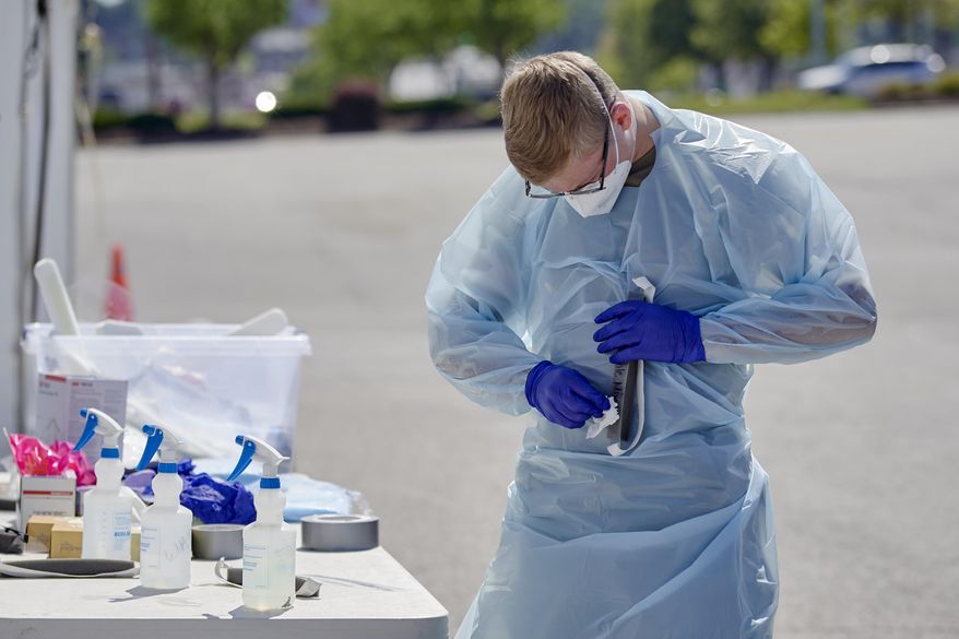 A nurse sanitizes his face shield at a coronavirus testing site in Omaha, Neb., Wednesday, July 8, 2020. Vice President Mike Pence says the U.S. government will issue guidance encouraging front-line health care workers to reuse personal protective equipment. Pence added that PPE supplies remain "very strong" but the Trump administration will be encouraging healthcare workers "to use some of the best practices" to "preserve and reuse" face masks and other protective equipment. (AP Photo/Nati Harnik)