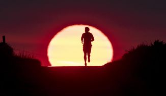 FILE - In this June 27, 2019 file photo a man runs on a small path as the sun rises in Frankfurt, Germany. The world could see average global temperatures 1.5 degrees Celsius (2.7 Fahrenheit) above the pre-industrial average for the first time in the coming five years, the U.N. weather agency said Thursday. The 1.5-C mark is a key threshold that countries have agreed to limit global warming to, if possible. Scientists say average temperatures around the world are already at least 1 C higher now than during the period from 1850-1900 because of man-made greenhouse emissions.  (AP Photo/Michael Probst, file)