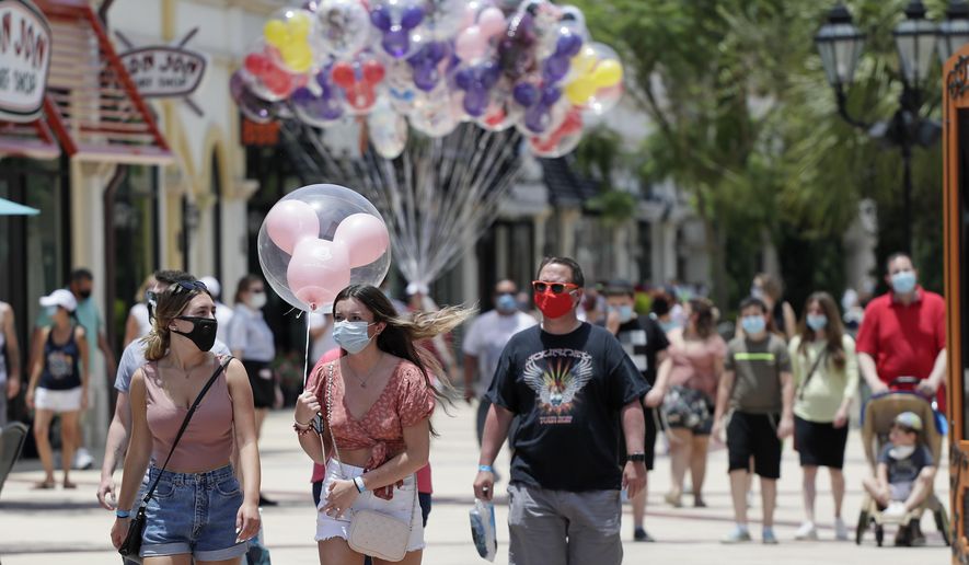 FILE - In this June 16, 2020, file photo, guests required to wear masks because of the coronavirus stroll through the Disney Springs shopping, dining and entertainment complex in Lake Buena Vista, Fla. Magic Kingdom and Animal Kingdom will reopen on July 11. In May, the company opened Disney Springs. (AP Photo/John Raoux, File)