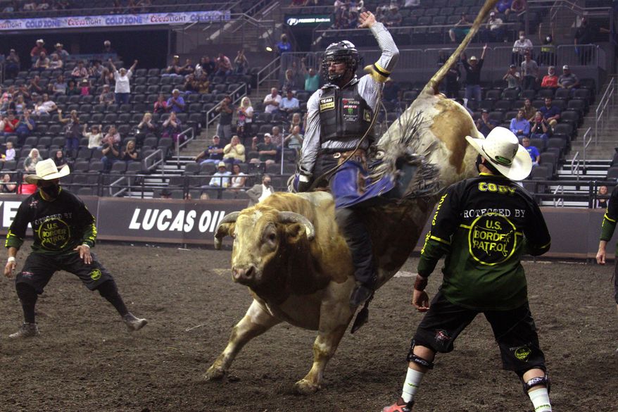 Lane Lasley rides a bull in the Monster Energy Team Challenge in Sioux Falls, S.D., Friday.July 10, 2020, as Professional Bull Riders welcomed just over 1,000 fans into the arena that usually holds 9,000. (AP Photo/Stephen Groves)