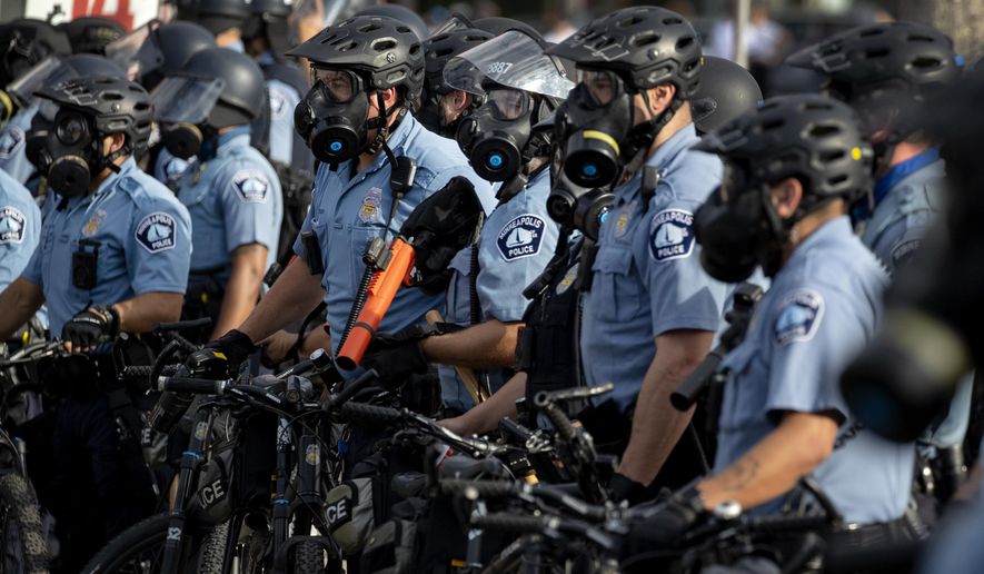 In this May 27, 2020, file photo, police gather en masse as protests continue at the Minneapolis 3rd Police Precinct in Minneapolis. More than 150 Minneapolis police officers have started the process of filing for disability claims since the death of George Floyd and the ensuing unrest in the city, with the majority citing post-traumatic stress disorder as the reason for their planned departure, according to an attorney representing the officers. (Carlos Gonzalez/Star Tribune via AP, File)  **FILE**