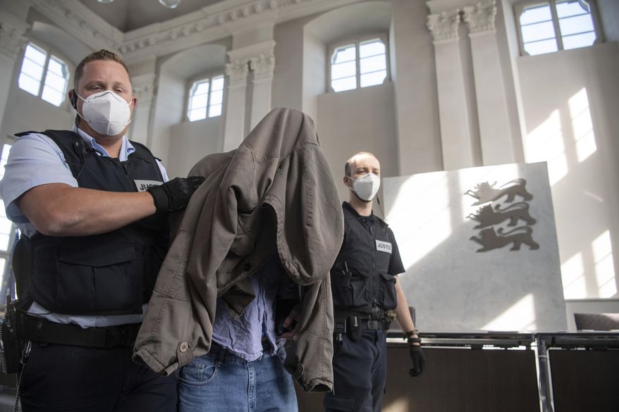 The accused in the trial of a six-time murder in Rot am See is led to his seat in a hall of the regional court in Ellwangen, Germany, Friday, July 10, 2020. The young man is said to have killed his parents, two half-brothers and sisters as well as his uncle and aunt at the end of January 2020. The public prosecutor accuses the German of murder and attempted murder. (Marijan Murat/dpa via AP)