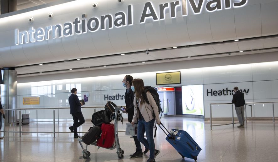 FILE - In this file photo dated Monday, June 8, 2020, passengers wearing face masks arrive at London&#x27;s Heathrow Airport.  Britain’s airports are much less busy than they would otherwise be in any other year, but the traditional British summer getaway to the sun-soaked beaches is set to pick up steam as quarantine restrictions are removed to dozens of countries, Friday July 10, 2020. (AP Photo/Matt Dunham, File)