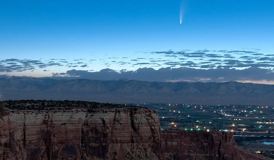 Comet Neowise soars in the horizon of the early morning sky in this view from the near the grand view lookout at the Colorado National Monument west of Grand Junction, Colo., Thursday, July 9, 2020. The newly discovered comet is streaking past Earth, providing a celestial nighttime show after buzzing the sun and expanding its tail. (Conrad Earnest via AP)