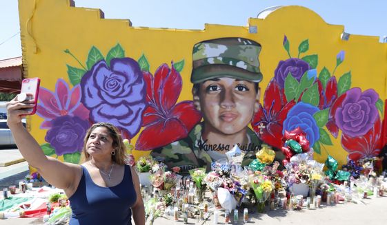 Irma Portillo makes a photo of herself and the mural of slain Army Spc. Vanessa Guillen painted on a wall in the south side of Fort Worth, Texas, Saturday, July 11, 2020. U.S. Army officials say they will begin an independent review of the command climate at Fort Hood, examining claims and historical data of discrimination, harassment and assault, following calls for a more thorough investigation into the killing of the soldier from the Texas base. (AP Photo/LM Otero)