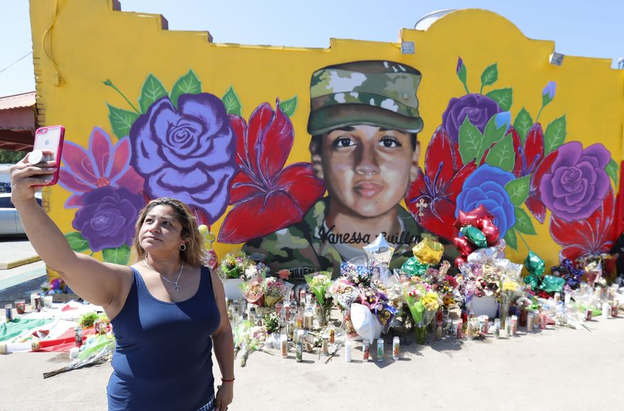 Irma Portillo makes a photo of herself and the mural of slain Army Spc. Vanessa Guillen painted on a wall in the south side of Fort Worth, Texas, Saturday, July 11, 2020. U.S. Army officials say they will begin an independent review of the command climate at Fort Hood, examining claims and historical data of discrimination, harassment and assault, following calls for a more thorough investigation into the killing of the soldier from the Texas base. (AP Photo/LM Otero)