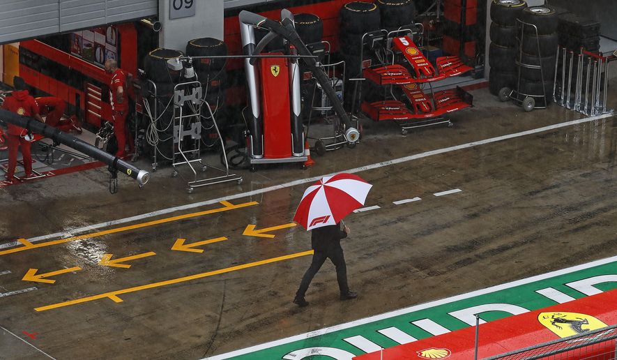 A man with an umbrella walks in the rain in the pit lane prior the delayed third practice session for the Styrian Formula One Grand Prix at the Red Bull Ring racetrack in Spielberg, Austria, Saturday, July 11, 2020. The Styrian F1 Grand Prix will be held on Sunday. (Leonhard Foeger/Pool via AP)