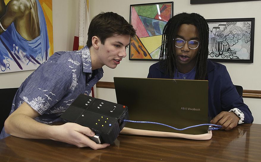 Alex Johnson, left, and Jonathan Walker operate a device they invented that turns text into braille on Thursday, Feb. 13, 2020 in Panama City, Fla. The two high school students submitted their device with a video presentation to the national Invention Convention and were awarded the opportunity to receive a patent. (Patti Blake/News Herald via AP)