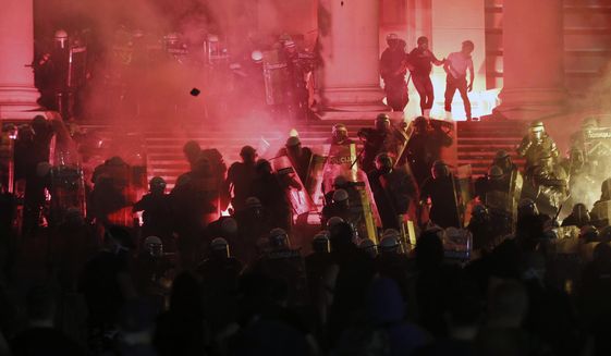 Protesters clash with riot police on the steps of the Serbian parliament during a protest in Belgrade, Serbia, Friday, July 10 2020. Hundreds of demonstrators tried to storm Serbia&#39;s parliament on Friday, clashing with police who fired tear gas during the fourth night of protests against the president&#39;s increasingly authoritarian rule. The protests started on Tuesday when President Aleksandar Vucic announced that Belgrade would be placed under a new three-day lockdown following a second wave of confirmed coronavirus infections. (AP Photo/Darko Vojinovic)