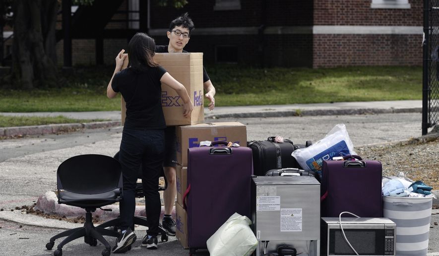 Duke freshman Feng Cong from Singapore and Cassie Lu from Thailand carry a box of their belongings to a pile as they move out of his dorm at Duke University. Sunday, March 15, 2020 in Durham, N.C.. Cong will be returning home to Singapore and Lu to Thailand since students are being asked to move out and complete classes online for the rest of the semester due to coronavirus. (Scott Sharpe/The News &amp;amp; Observer via AP)