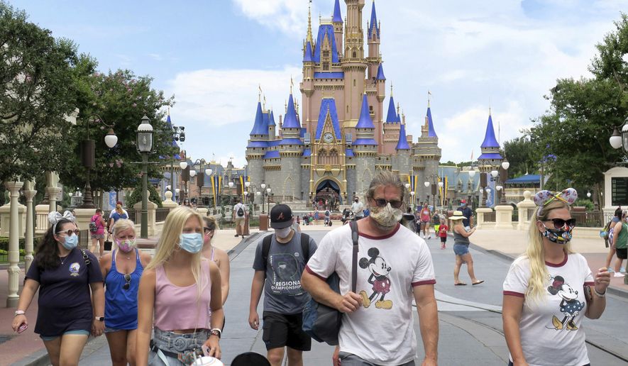 Guests wear masks as required to attend the official reopening day of the Magic Kingdom at Walt Disney World in Lake Buena Vista, Fla., Saturday, July 11, 2020. Disney reopened two Florida parks, the Magic Kingdom and Animal Kingdom, Saturday, with limited capacity and safety protocols in place in response to the coronavirus pandemic. (Joe Burbank/Orlando Sentinel via AP)