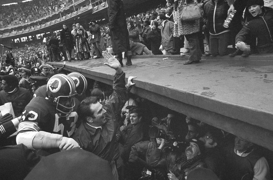 FILE- In this Dec. 24, 1972, file photo, Washington Redskins coach George Allen waves to fans at Robert F. Kennedy Stadium in Washington as he leaves the field following the team&#x27;s 16-3 win over the Green Bay Packesr in an NFL playoff game. At left is linebacker Harold McLinton. Washington’s NFL team will get rid of the name &quot;Redskins&quot; on Monday, July 13, according to multiple reports. It’s unclear when a new name will be revealed for one of the league’s oldest franchises. The team launched a &quot;thorough review&quot; of the name July 3.(AP Photo, File)