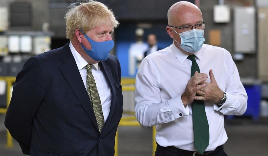 Britain's Prime Minister Boris Johnson, wearing a face mask, talks with CEO London Ambulance Service Garrett Emmerson, right, during a visit to the headquarters of the London Ambulance Service NHS Trust in London, Monday July 13, 2020. (Ben Stansall/Pool via AP)