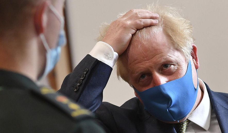 Britain's Prime Minister Boris Johnson, wearing a face mask, talks with a paramedic during a visit to the headquarters of the London Ambulance Service NHS Trust in London, Monday July 13, 2020. (Ben Stansall/Pool via AP)