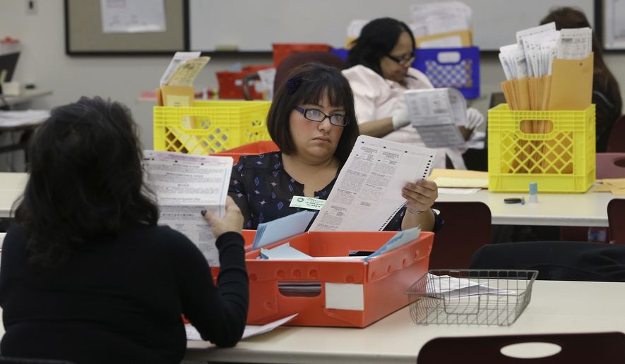 FILE - In this Wednesday, Nov. 12, 2014, file photo, Lydia Harris, a temporary worker at the Sacramento Registrar of Voters, looks over a mail-in ballot before it is sent to be counted in Sacramento, Calif. Over 100,000 mail-in ballots were rejected by election officials in California's March 2020 presidential primary, highlighting a glaring gap in the effort to ensure every vote is counted as a national dispute rages over the integrity of vote-by-mail elections. (AP Photo/Rich Pedroncelli, File)