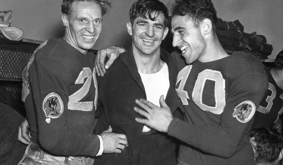 FILE - In this Dec. 12, 1937, file photo, Washington Redskins quarterback Sammy Baugh, center, celebrates with teammates Cliff Battles, left, and Wayne Millner in the locker room after the Redskins defeated the Chicago Bears 28-21 in the NFL championship football game in Chicago. Washington’s NFL team will get rid of the name &amp;quot;Redskins&amp;quot; on Monday, July 13, according to multiple reports. It’s unclear when a new name will be revealed for one of the league’s oldest franchises. The team launched a &amp;quot;thorough review&amp;quot; of the name July 3.(AP Photo, File)