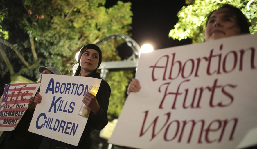 File-Ariana Marsh, center, and Katie Davis, right, participate in a pro-life candlelight vigil organized by Students for Life at UGA held to protest Roe v. Wade at the University of Georgia Arch, Tuesday, Jan. 24, 2017, in Athens, Ga. (John Roark/Athens Banner-Herald via AP, File)/Athens Banner-Herald via AP) ** FILE **