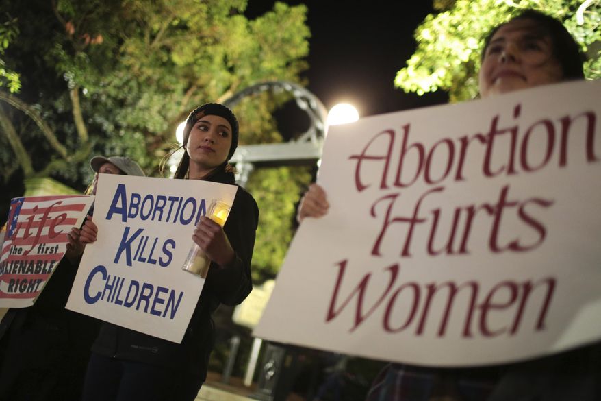 File-Ariana Marsh, center, and Katie Davis, right, participate in a pro-life candlelight vigil organized by Students for Life at UGA held to protest Roe v. Wade at the University of Georgia Arch, Tuesday, Jan. 24, 2017, in Athens, Ga. (John Roark/Athens Banner-Herald via AP, File)/Athens Banner-Herald via AP) ** FILE **