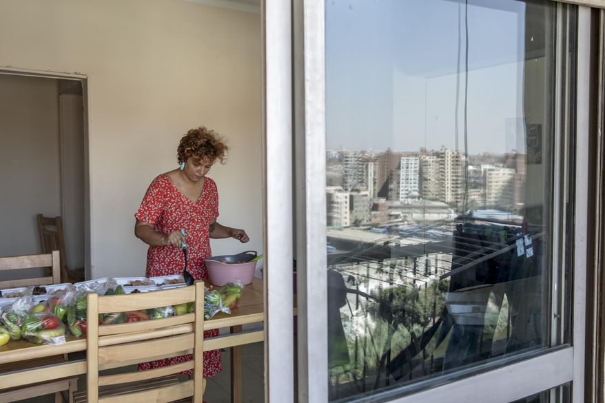 Basma Mostafa, a 30-year-old journalist who founded an initiative that sends freshly home cooked meals to quarantined coronavirus patients, package food at her friend's apartment, in Cairo, Egypt. Saturday, July 11, 2020.  Mostafa, who works with others to coordinate the volunteer effort, said she got the idea of helping out when she was going through a difficult time. "I thought that to alleviate my suffering, I can engage with the suffering of others and feel more for them," she said. "I derive my strength and perseverance from the patients." (AP Photo/Nariman El-Mofty)