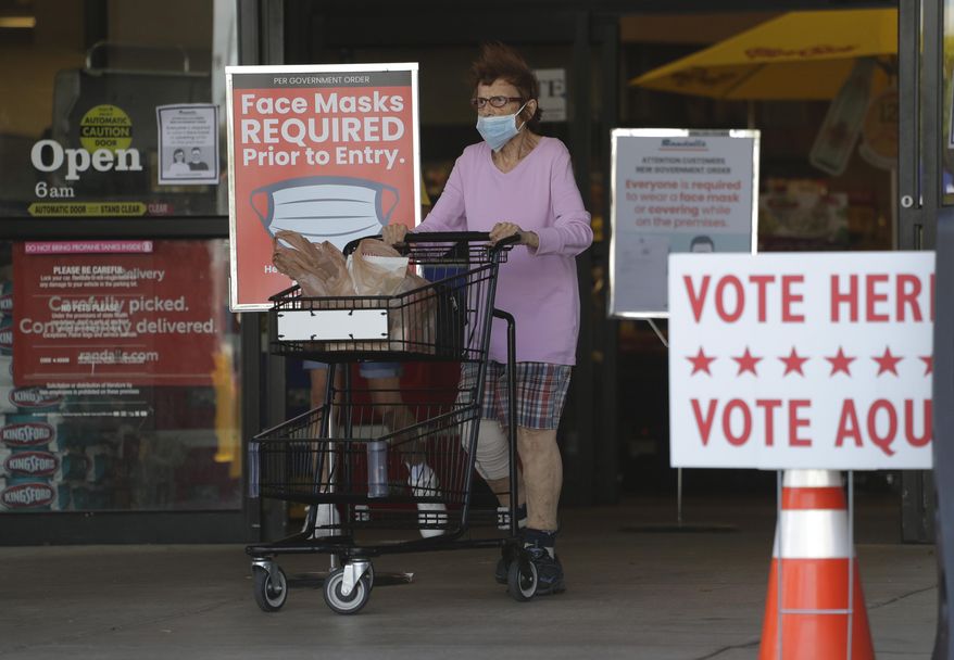 A shopper wearing a mask for protection against COVID-19 leaves a grocery store that is also searing as an early polling site, Thursday, July 9, 2020, in Austin, Texas. (AP Photo/Eric Gay)