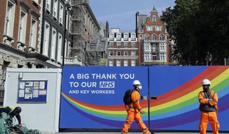 FILE - In this Thursday, May 7, 2020 file photo, a  construction worker passes a sign thanking the NHS in London, as the country in is lockdown to prevent the spread of coronavirus. The British economy grew by far less than anticipated during May, dampening hopes that the recovery from what is set to be one of the country’s deepest recessions in centuries will be rapid. The Office for National Statistics said Tuesday, July 14, 2020, that the economy grew by 1.8% in May from the previous month after some easing of the lockdown, such as encouraging those in construction or manufacturing to return to work.  (AP Photo/Kirsty Wigglesworth, File)
