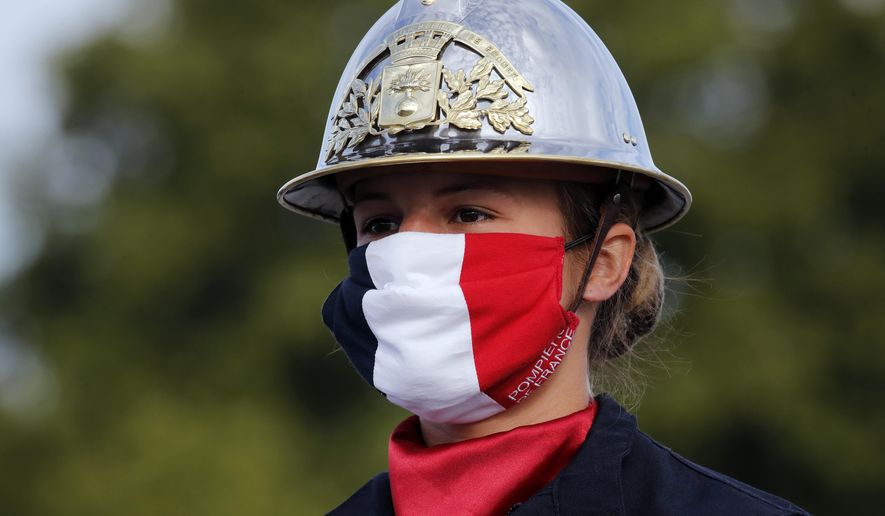 A firefighter wears a face mask with the colors of the French flag, prior to the Bastille Day parade Tuesday, July 14, 2020 on the Champs Elysees avenue in Paris. France are honoring nurses, ambulance drivers, supermarket cashiers and others on its biggest national holiday Tuesday. Bastille Day&#x27;s usual grandiose military parade in Paris is being redesigned this year to celebrate heroes of the coronavirus pandemic. (AP Photo/Christophe Ena, Pool)