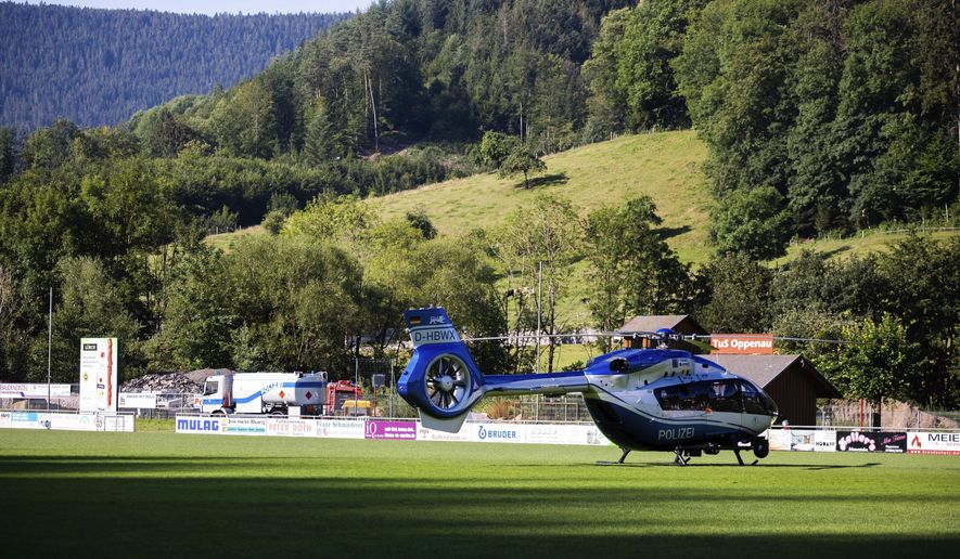 A police helicopter stands on a sports field in Oppenau, southern Germany, Tuesday, July 14, 2020. Authorities in Germany say they have deployed hundreds of police in the hunt for a 31-year-old man who disarmed four officers at gunpoint on Sunday, July 12, 2020. (Philipp von Ditfurth/dpa via AP)/dpa via AP)