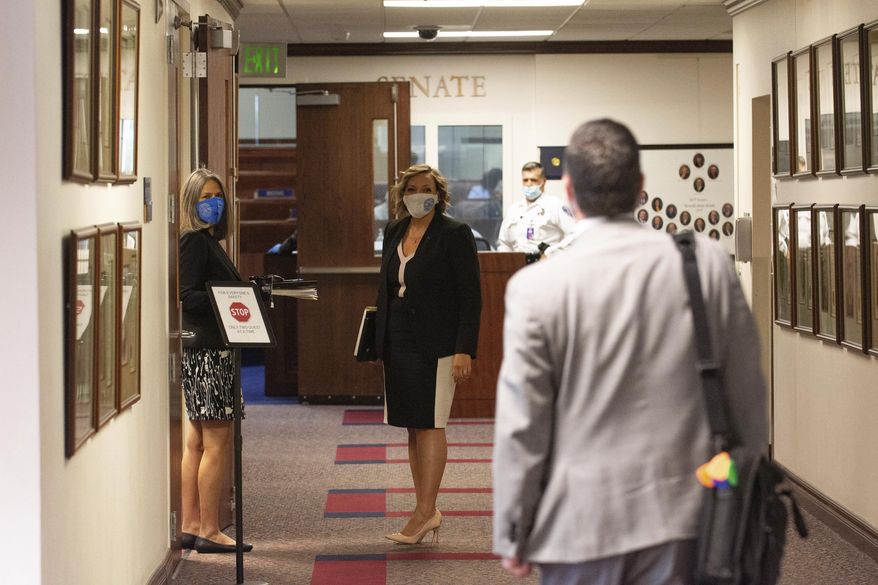 Nevada Assemblyman Steve Yeager, right calls out to state Sens. Julia Ratti, left, and Nicole Cannizzaro, in the hallway outside the Senate chambers on the sixth day of the 31st Special Session of the Nevada Legislature in Carson City, Nev., Tuesday, July 14, 2020. (David Calvert/The Nevada Independent via AP, Pool)