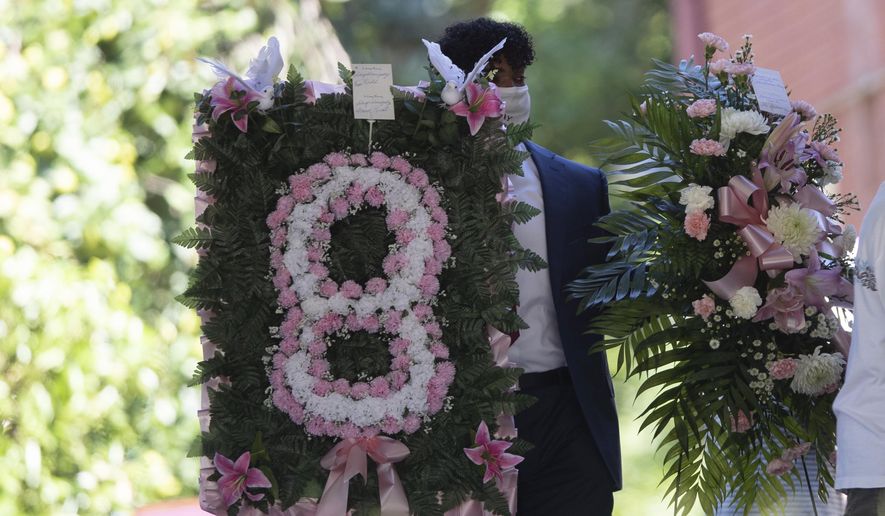 A man carries flowers into a viewing for 8-year-old Secoriea Turner, who was fatally shot in Atlanta on July 4th near the Wendy's site where Rayshard Brooks was killed the previous month Tuesday, July 14, 2020, in South Fulton, Ga. (AP Photo/John Bazemore)