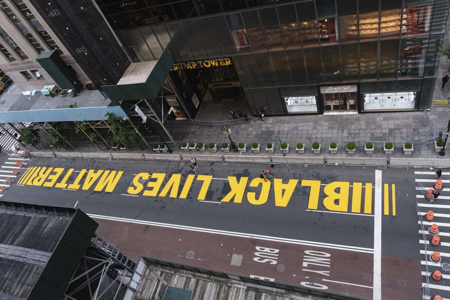 Pedestrians walk on a Black Lives Matter mural painted in front of Trump Tower, Friday, July 10, 2020, in New York. (AP Photo/Yuki Iwamura)