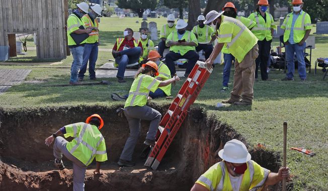 Workers climb out of the excavation site as work continues on an excavation of a potential unmarked mass grave from the 1921 Tulsa Race Massacre, at Oaklawn Cemetery in Tulsa, Okla., Tuesday, July 14, 2020. On May 31 and June 1 in 1921, white residents looted and burned Tulsa’s black Greenwood district, killing as many as 300 people with many believed buried in mass graves.   (AP Photo/Sue Ogrocki)