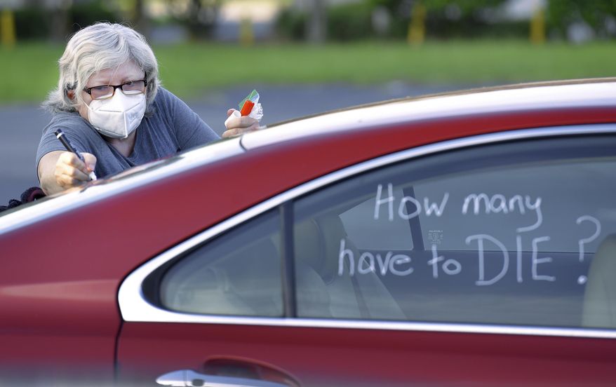 Registered Nurse Laure Hale writes on her car as she is preparing to take part in a motorcade protest to the Duval County School Board building, Tuesday, July 14, 2020 in Jacksonville, Fla. Duval County teachers and their supporters gathered in a parking lot before they drove to the Duval County School Board Building and protest plans of starting the upcoming school year with the rate of COVID-19 infections hitting record rates in Jacksonville. (Bob Self/The Florida Times-Union via AP)