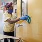 Amid concerns of the spread of COVID-19, Alma Odong wears a mask as she cleans a classroom at Wylie High School in Wylie, Texas. The cost of bringing students back to classrooms is proving a major stumbling block to safely reopening schools across the U.S. (AP Photo/LM Otero, File)