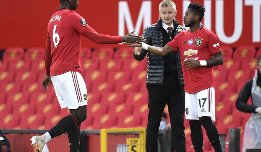 Manchester United's Paul Pogba, left, gestures to teammate Fred as he is substituted during the English Premier League soccer match between Manchester United and Southampton at Old Trafford in Manchester, England, Monday, July 13, 2020. (AP Photo/Dave Thompson,Pool)