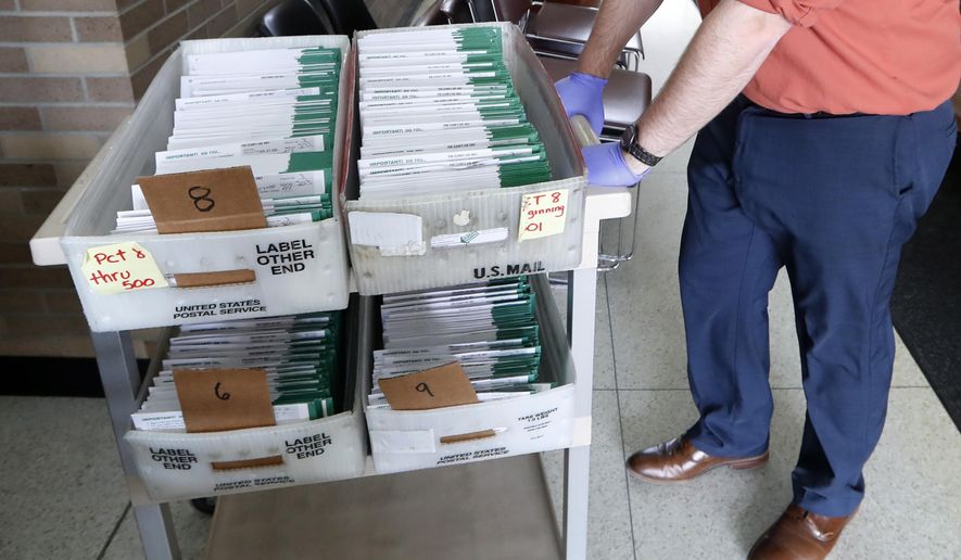 FILE - In this May 5, 2020, file photo, Jordan Smellie moves absentee ballots to be counted at City Hall in Garden City, Mich. The Michigan appeals court has denied a request to require the counting of absentee ballots received after the time polls close on Election Day. The ruling says the deadline remains intact despite voters' approval of a constitutional amendment that expanded mail-in voting. (AP Photo/Paul Sancya, File)