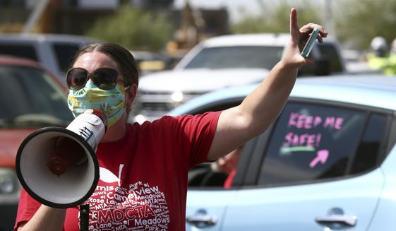 In this file photo from July 15, 2020, local teacher Lisa Vaaler joins other teachers as they hold a #Return2SchoolSafely Motor March protest in Phoenix. At that protest, several Arizona teachers voiced fears about returning to school in a state that continues to be ravaged by the coronavirus. (AP Photo/Ross D. Franklin)  ** FILE **