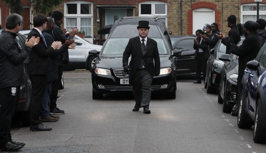 In this photo taken on Thursday, June 11, 2020, grass roots soccer referees form a guard of honour and clap as the hearse carrying the coffin of Jermaine Wright, a pharmacist and a referee of the Hackney Marshes grassroots football league, passes by, on the day of his funeral, in London. Wright, affectionately known as Mr. Hackney Marshes, served as both an on-field referee and a behind-the-scenes catalyst in the Hackney & Leyton Sunday Football League — as vice chairman, schedule secretary, results secretary, press officer, and head official before he died on April 27, 2020 from COVID-19. (AP Photo/Frank Augstein)