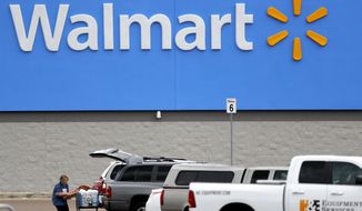 In this March 31, 2020, file photo, a woman pulls groceries from a cart to her vehicle outside of a Walmart store in Pearl, Miss. Walmart will require customers to wear face coverings at all of its namesake and Sam&#39;s Club stores. The company said the policy will go into effect on Monday, July 20, 2020, to allow time to inform stores and customers. (AP Photo/Julio Cortez, File)