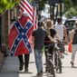 In this July 3, 2020, file photo, a man wears a Confederate flag while walking with others in Marion, Va. (Andre Teague/Bristol Herald Courier via AP, File)